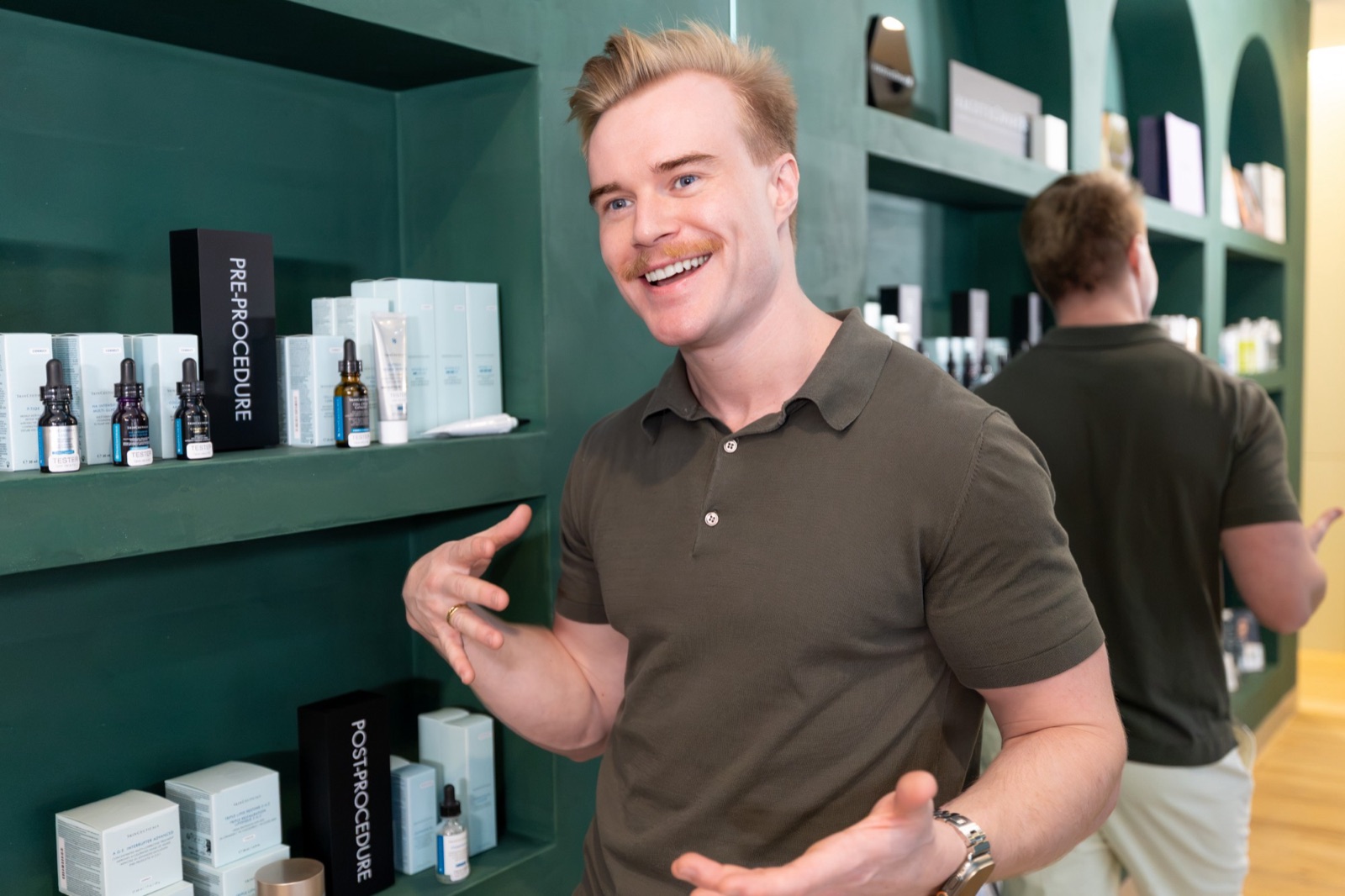 Dr Brandon talking in the Cleon clinic in Potts Point, in front of the green skincare shelves
