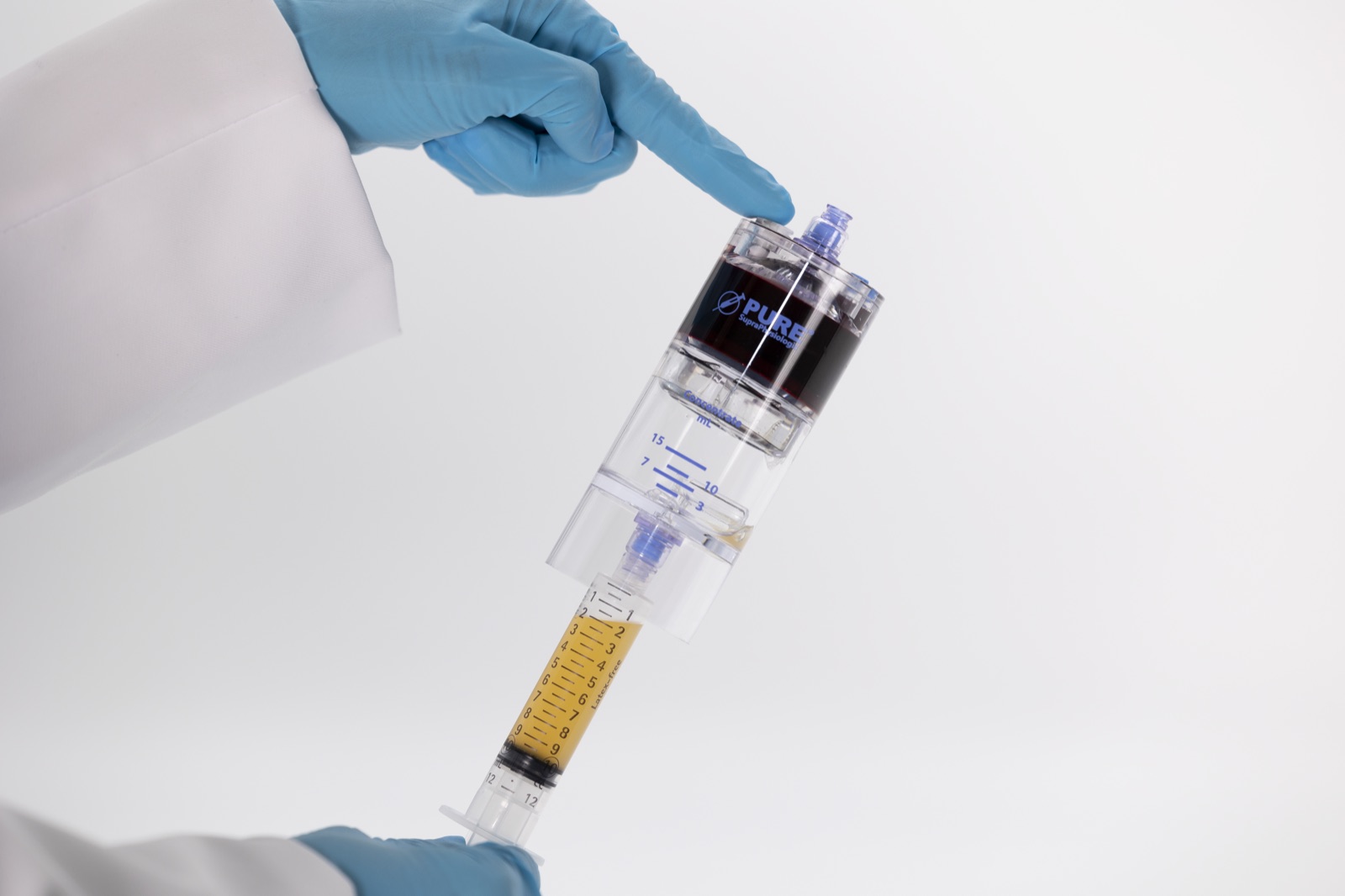 Gloved hands drawing golden platelet-rich plasma from an EmCyte PurePRP concentrator into a syringe
